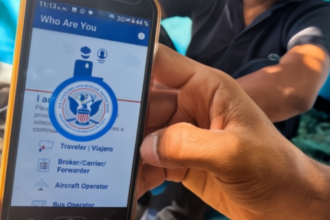 Mano sosteniendo celular con app de autodeportación y boleto de avión