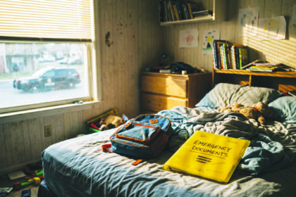 Habitación infantil vacía con una carpeta de documentos de emergencia sobre la cama, simbolizando a los niños separados de sus padres.