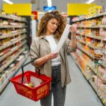 Joven mujer preocupada por el precio de su compra leyendo el recibo del supermercado